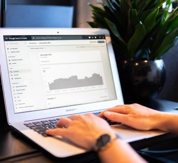 person using macbook air on brown wooden table